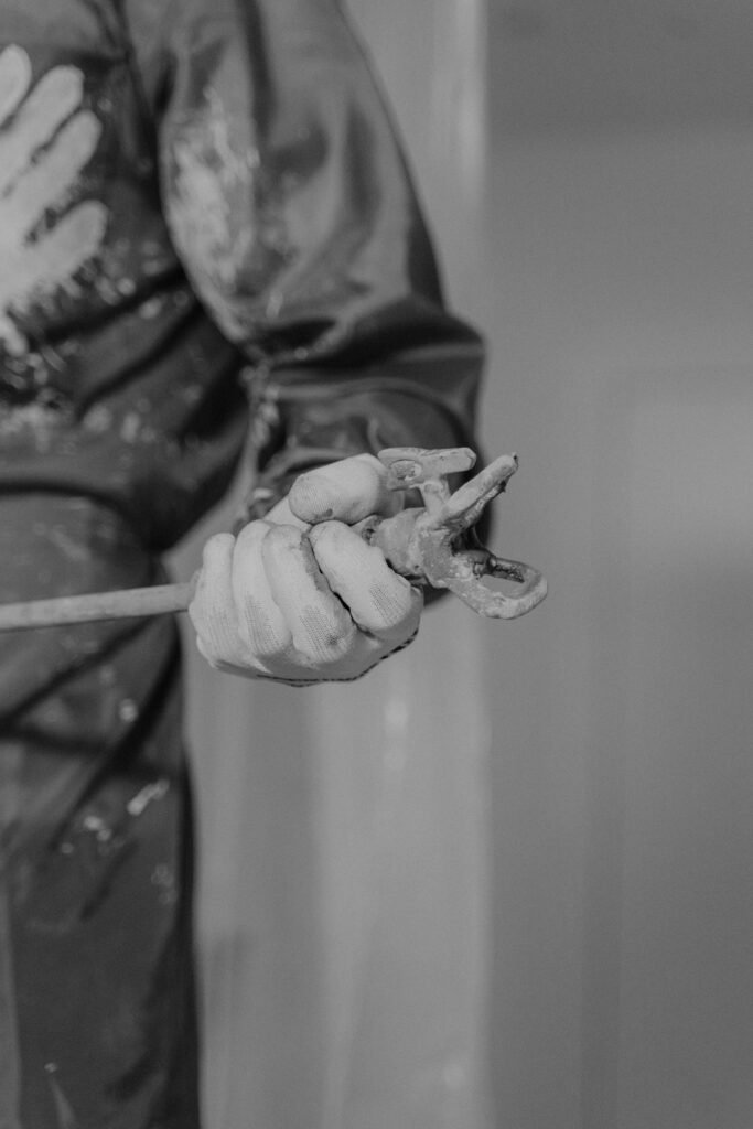 pexels-photo-6474348-6474348 Monochrome photo featuring a worker's hand gripping a wrench, symbolizing construction.